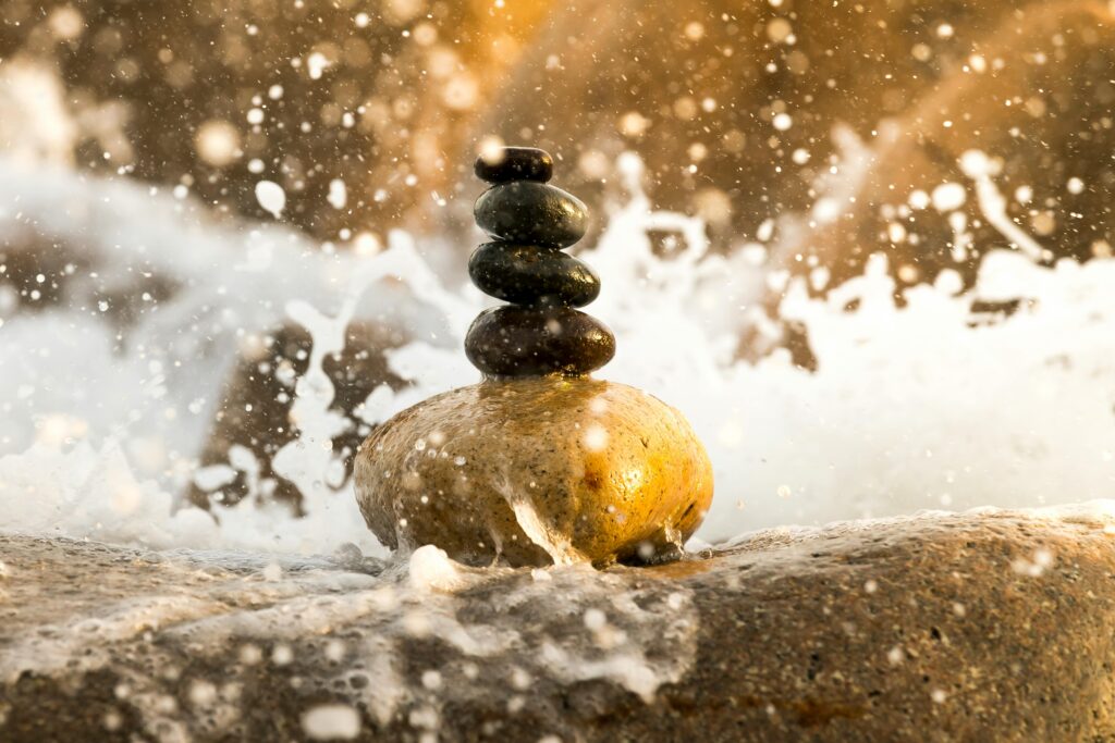Peaceful balance of stacked stones amidst splashing water, creating a zen-like ambiance.